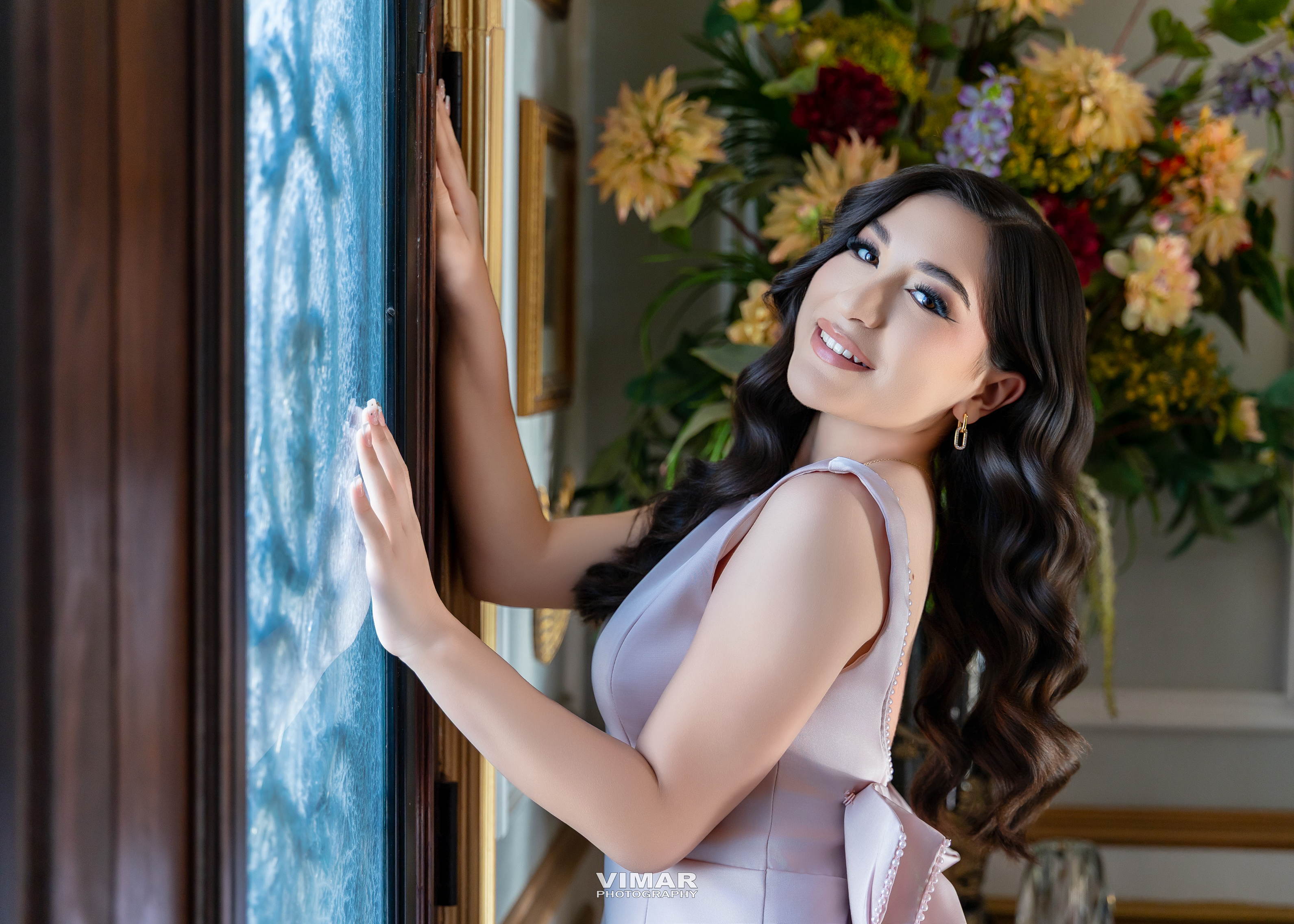 Madison Grace smiling beside a window in a soft pink dress